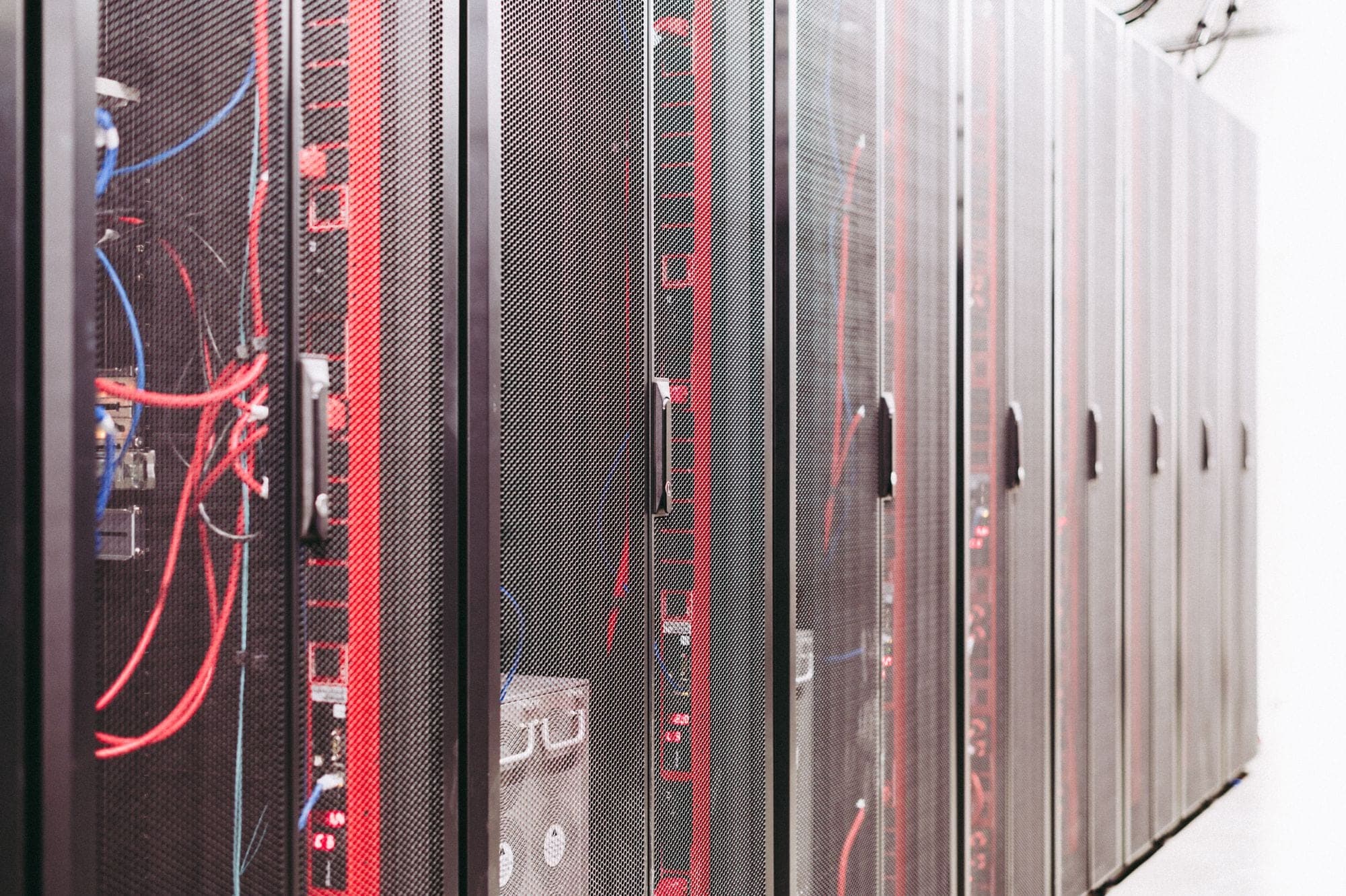 Rows of illuminated server racks receding down a data-centre aisle — the physical backbone of a live digital platform.
